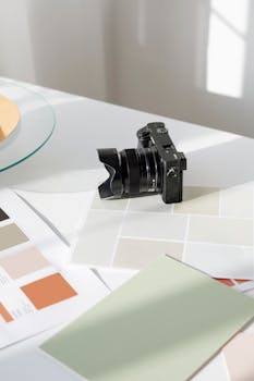 Digital camera resting on a desk with color swatches and design materials.