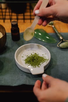 A person blends herbal powder for skincare treatment indoors.